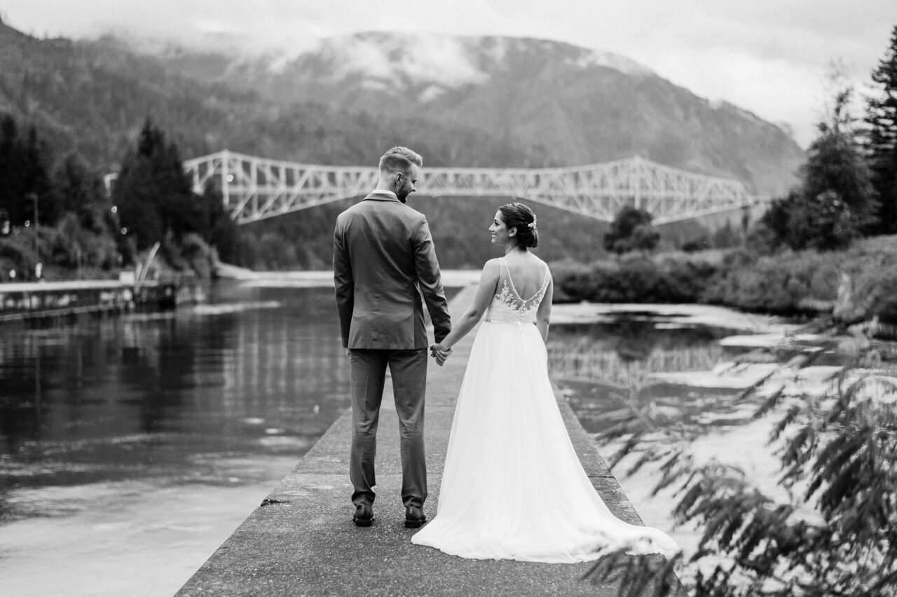  Bride and groom face bridge of the gods and cloudy Columbia gorge 