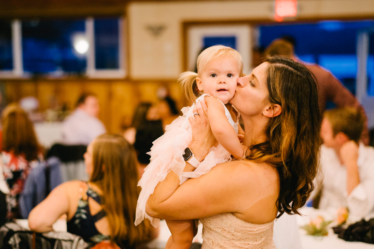 Mother kisses toddler in pink dress at wedding reception 