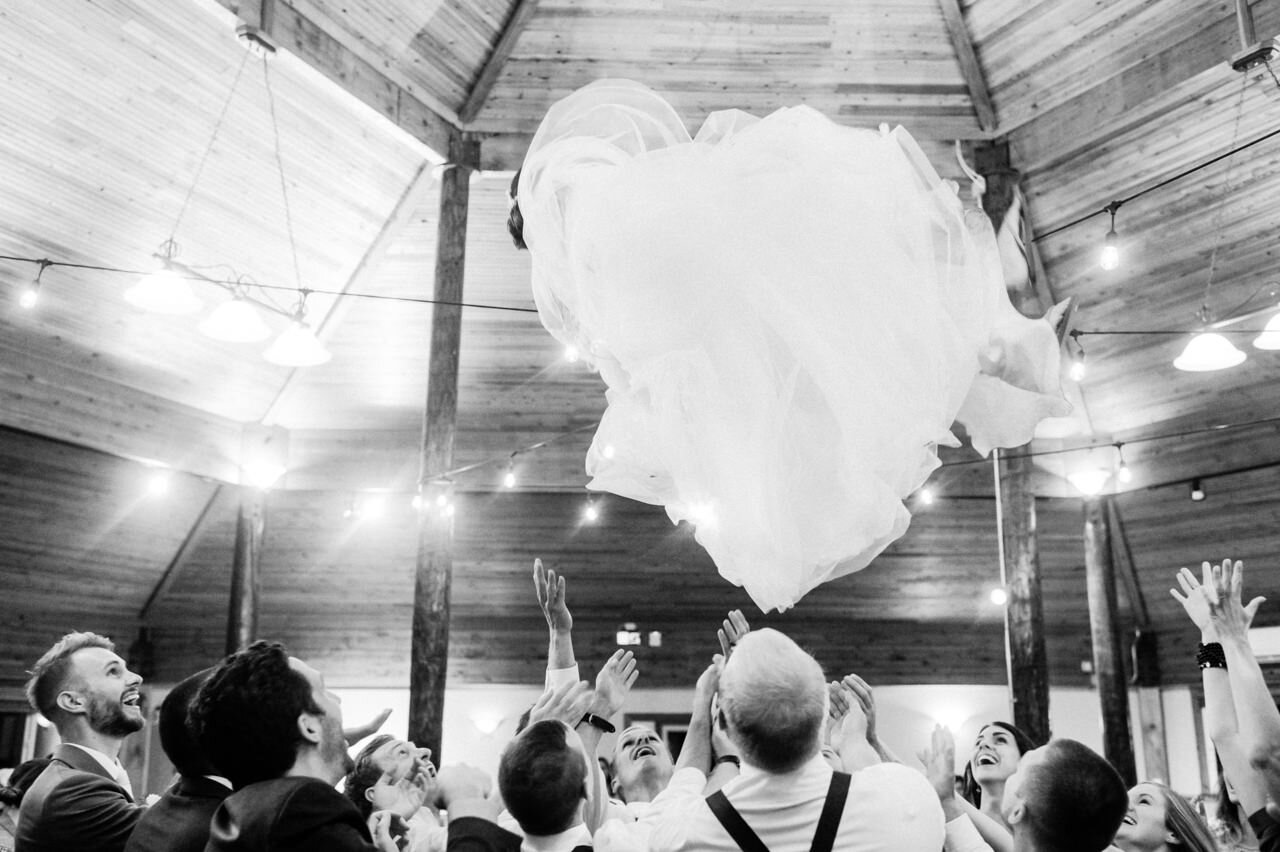  Bride tossed in air engulfed by wedding dress while groom smiles 