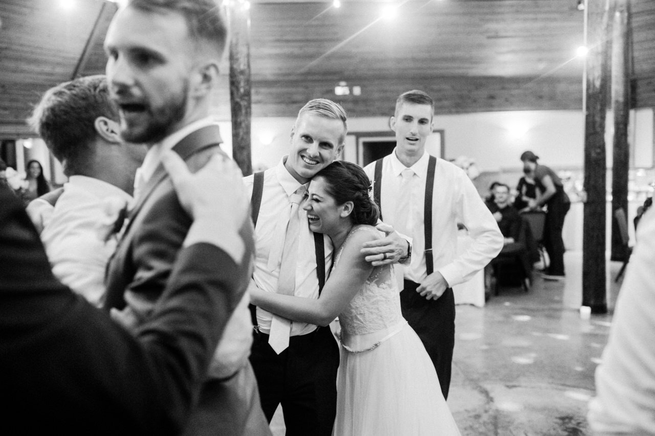  Bride laughs while hugging groomsman 