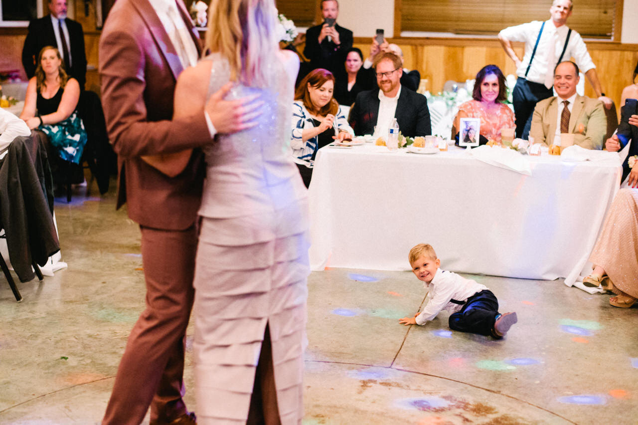  Child plays on the floor while groom dances with mother 