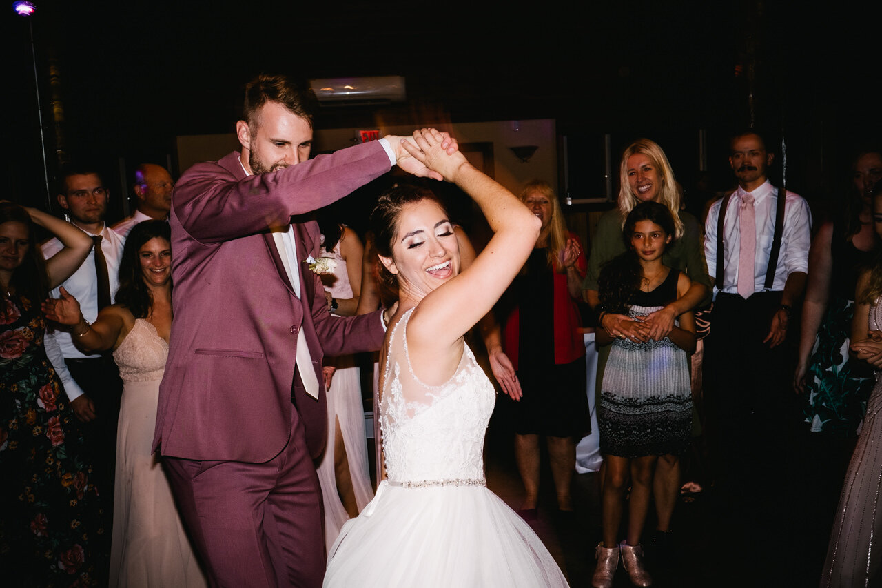  Bride spins with groom in purple suit during wedding party dance 