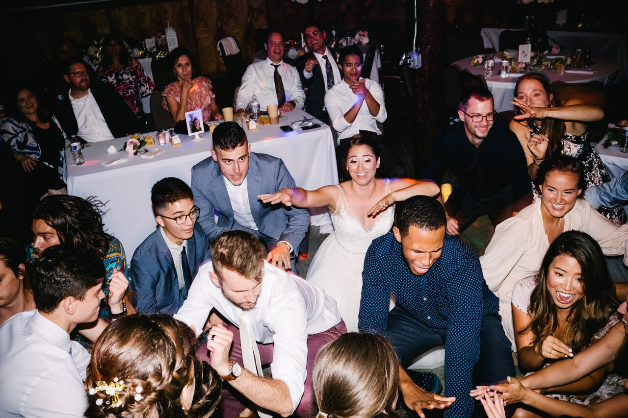  Bride, groom, and guests squat low on dance floor 