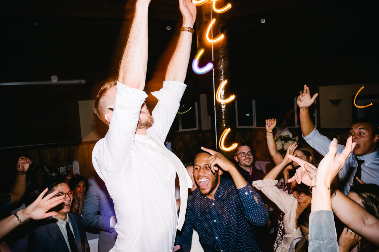  Groom jumps while wedding guests cheer on dance floor 