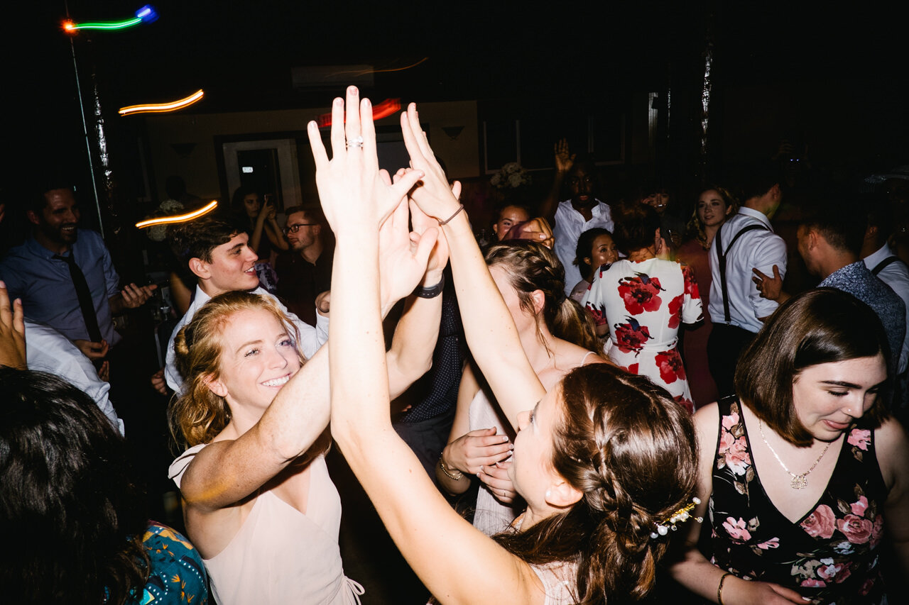  Bridesmaids clap hands in air on dance floor 