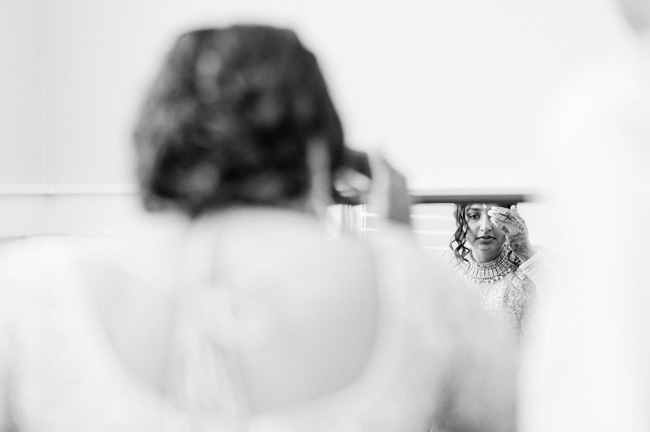  Reflection of Indian bride adjusting headpiece in mirror 