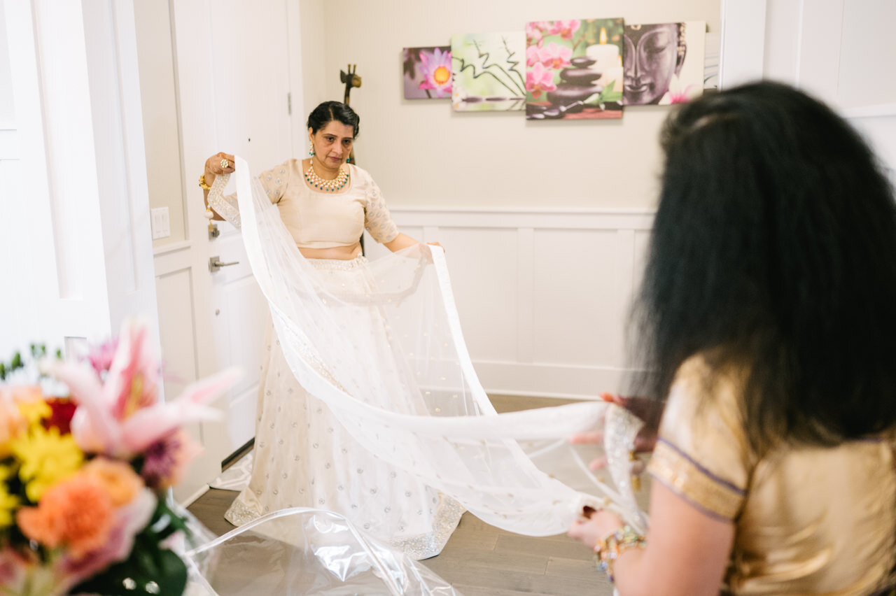 Bride's mother and auntie holds veil in home 