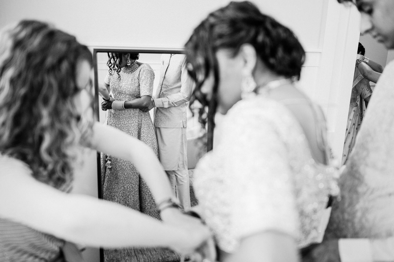  Indian bride adjusting sari in mirror 