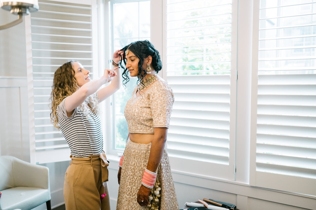  Bride's maid of honor adjusts hair in home 
