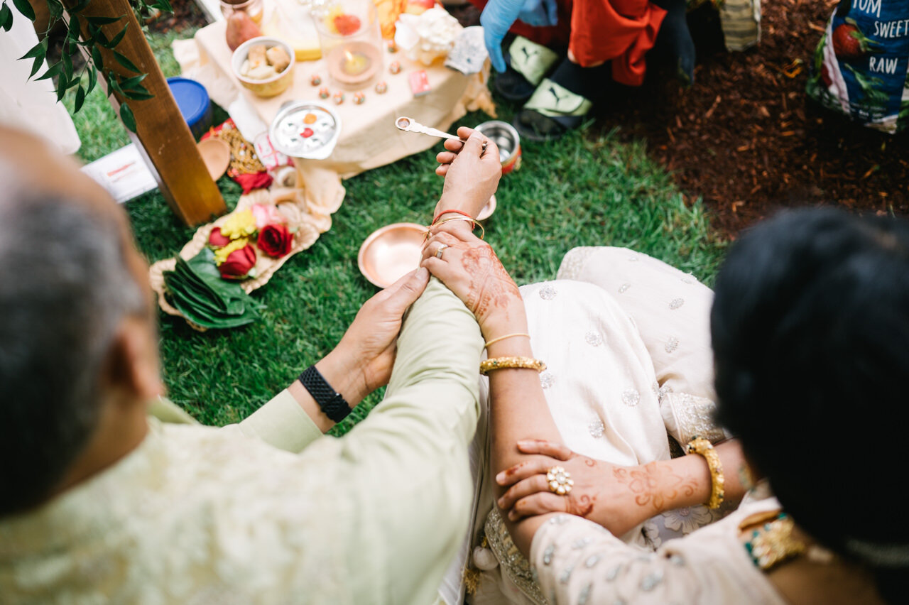  Hands of Indian brides parents scooping honey in spoon 