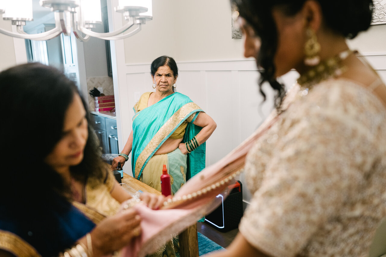  Auntie in teal and gold sari watches bride adjust her sari 