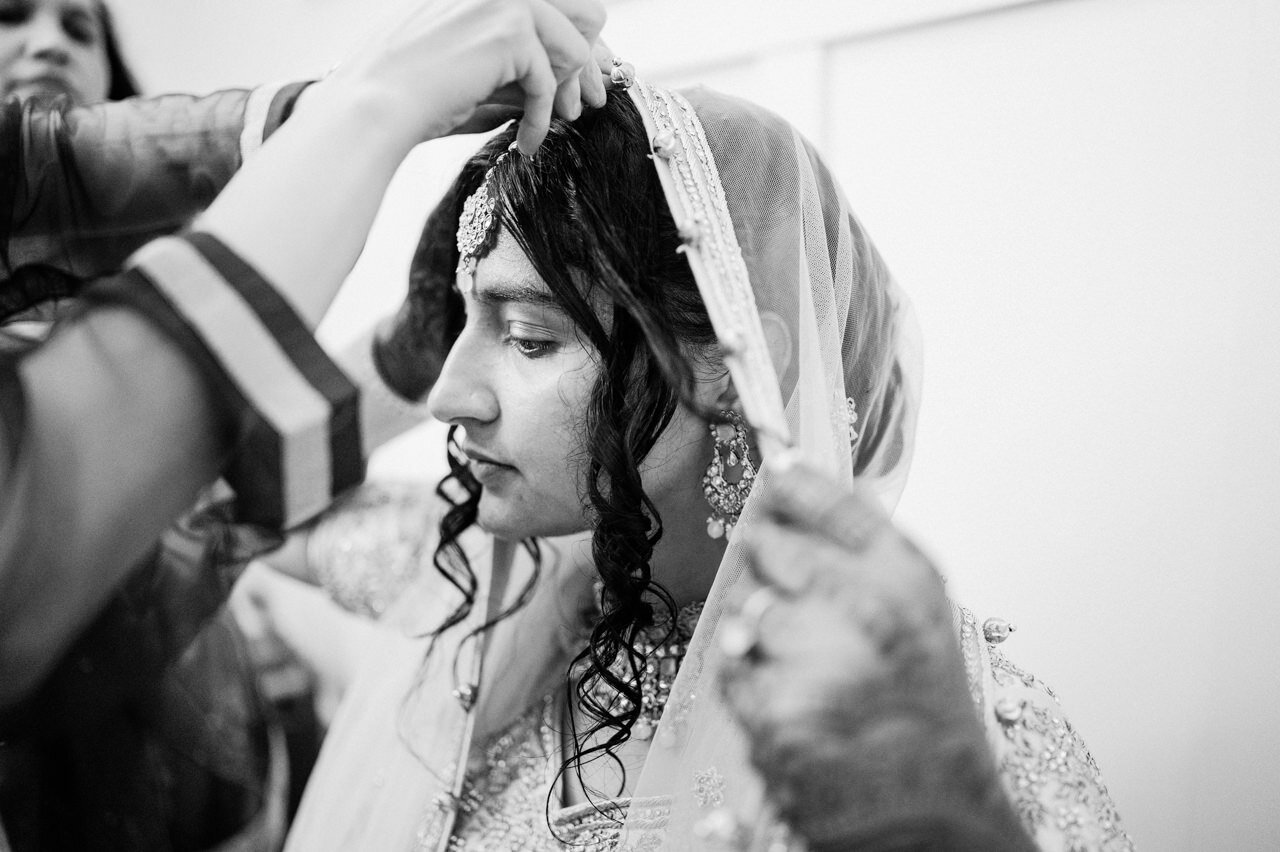  Hands adjust Indian wedding veil in black and white photograph 
