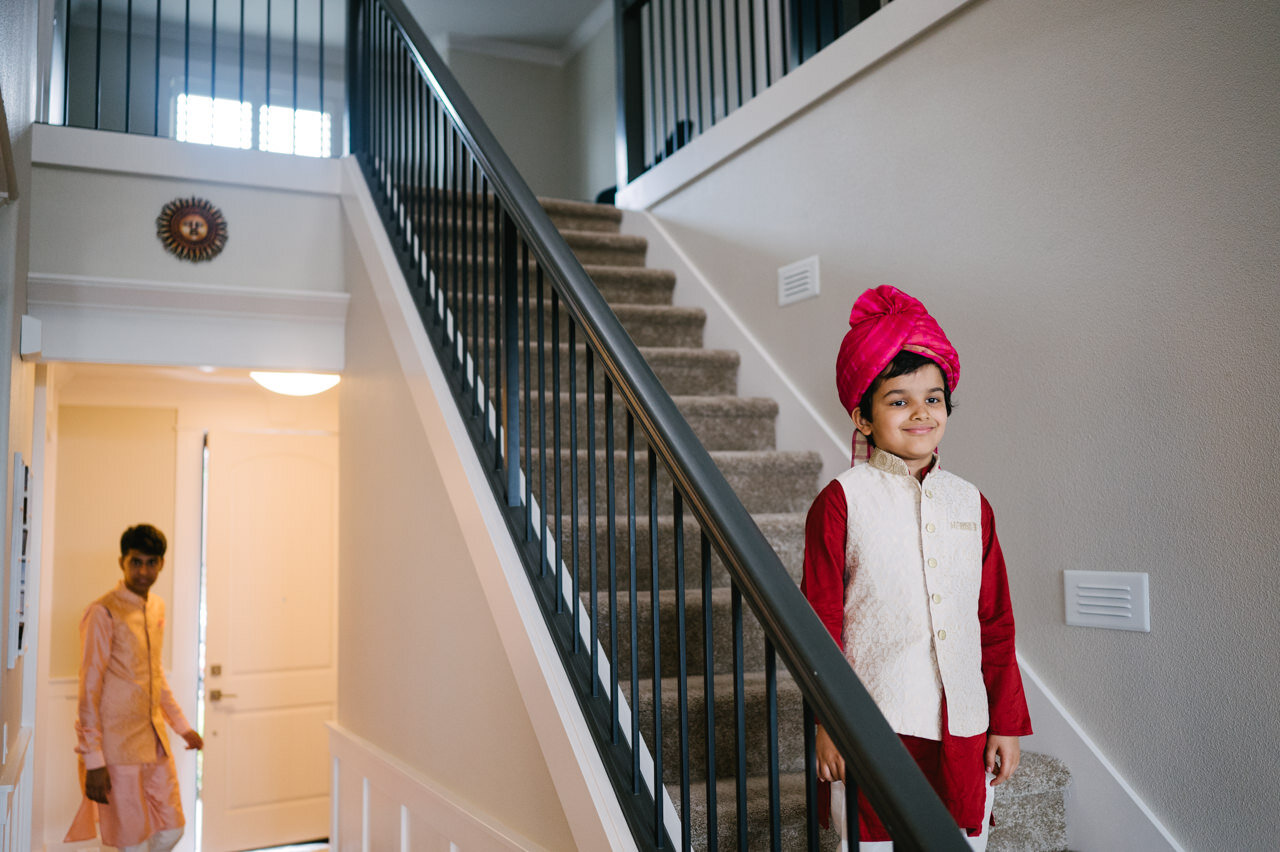  Indian boy in red turban smiles for photo on stairs 