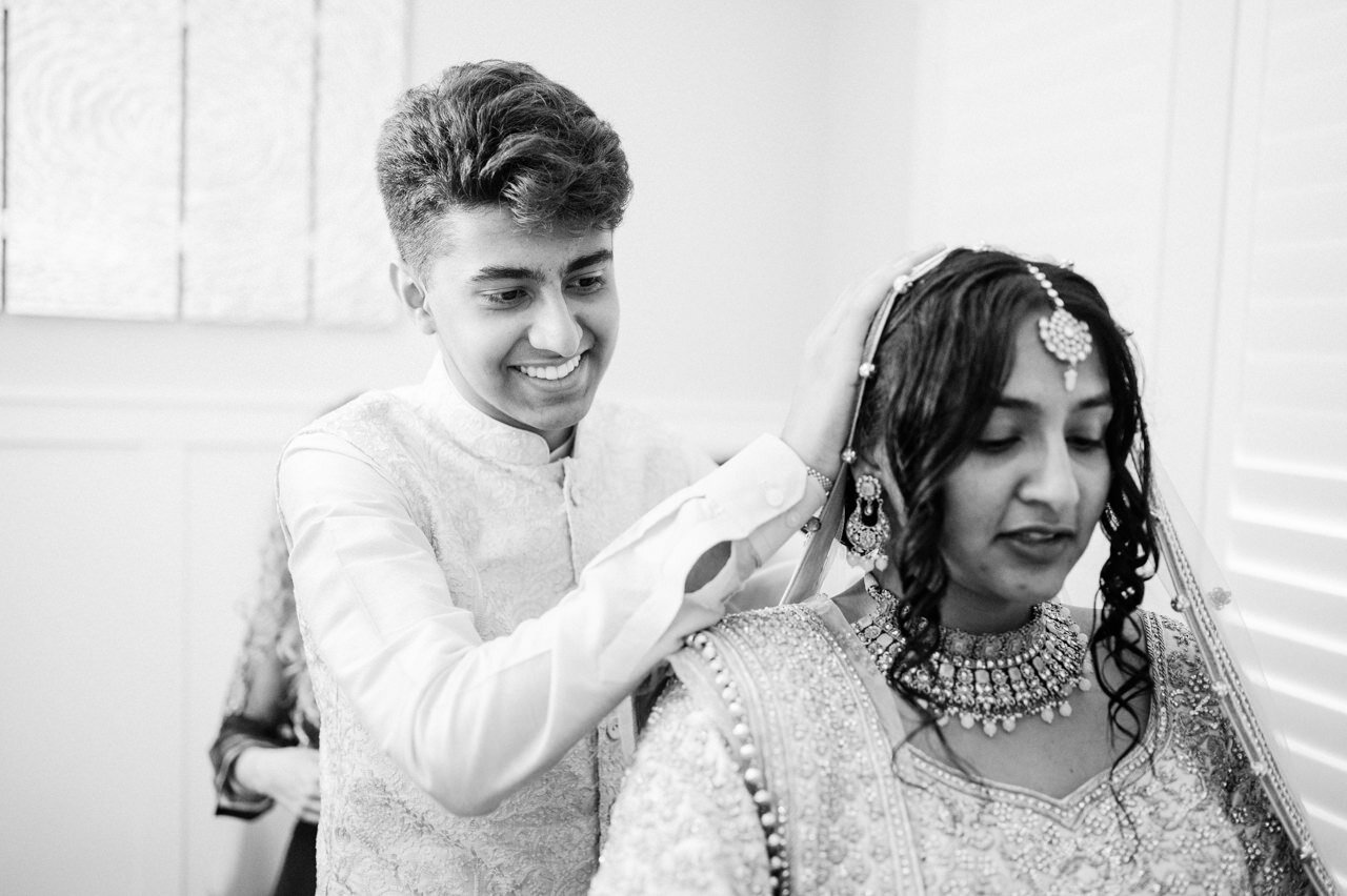  Bride's brother adjusts bride's veil in black and white 