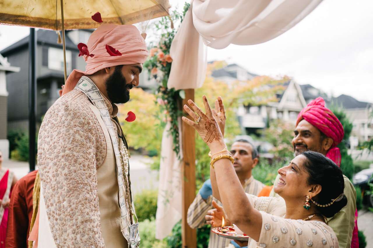  Bride's mother tosses red roses onto groom under wedding backdrop 