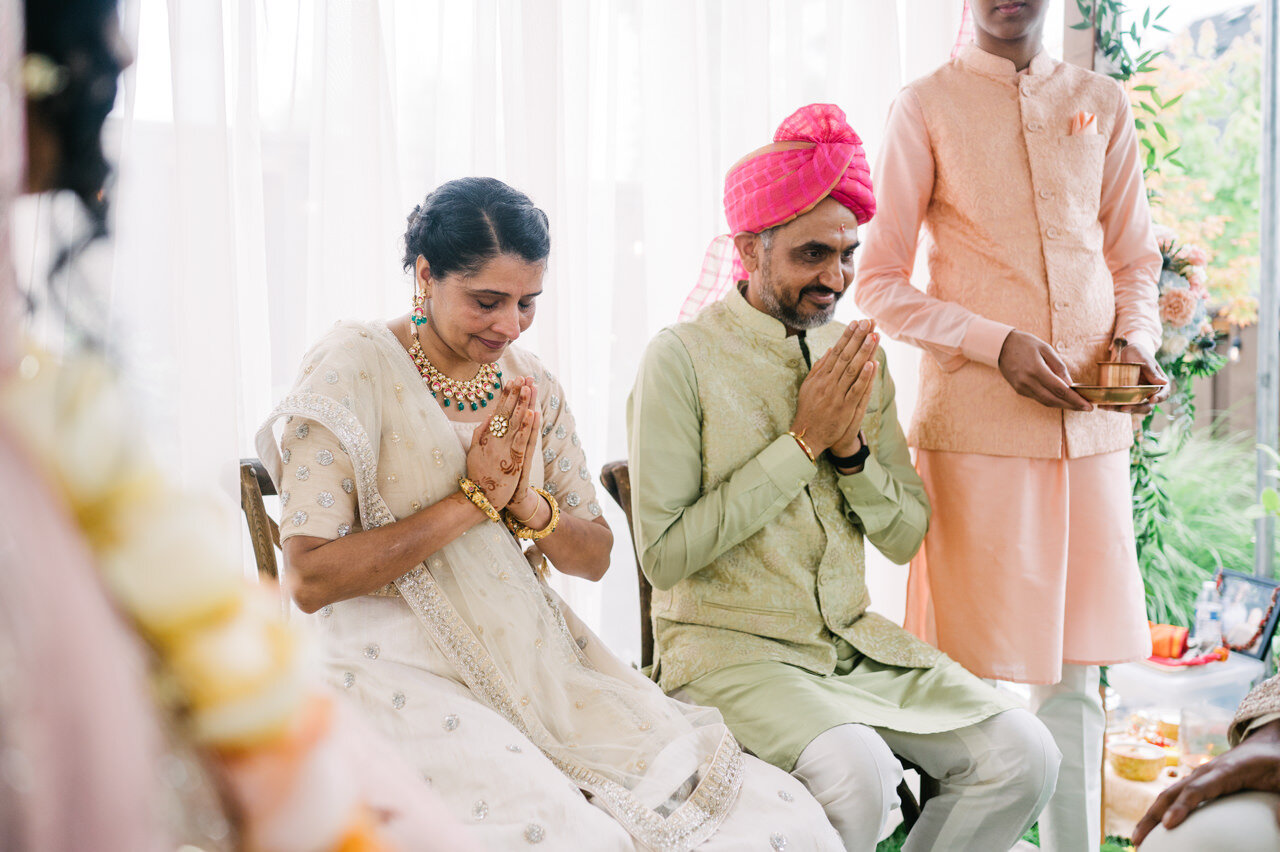  Bride parents clasp hands in ceremony under mandap 