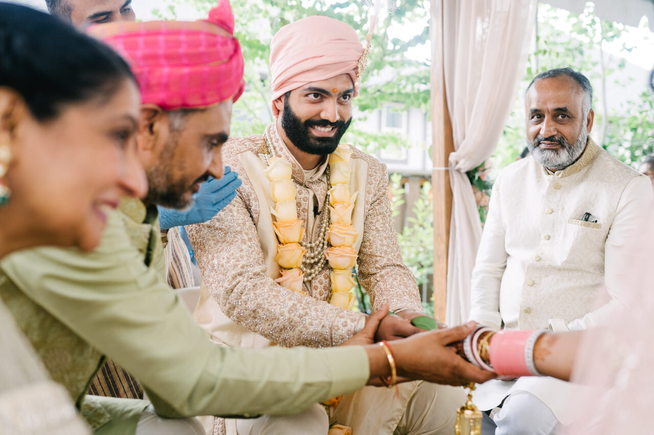  Groom smiles at bride during ceremony 