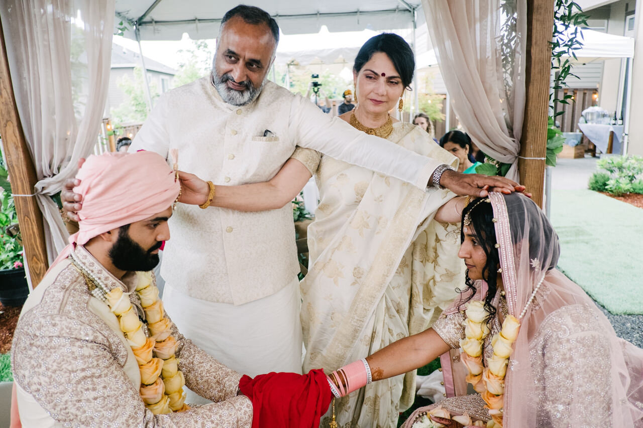  Bride and groom blessed by groom parents during indian wedding ceremony under mandap 
