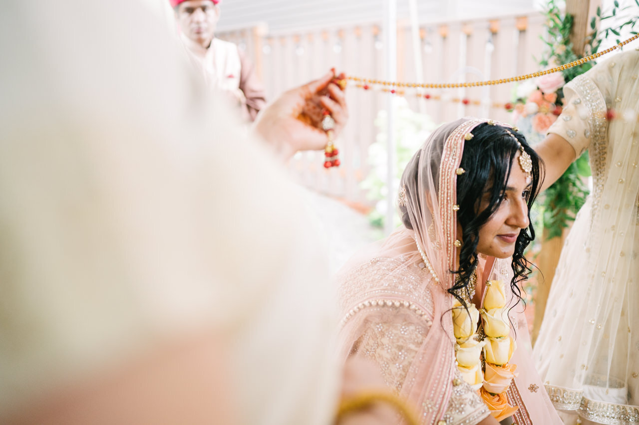  Bride looking at groom under beads during ceremony 