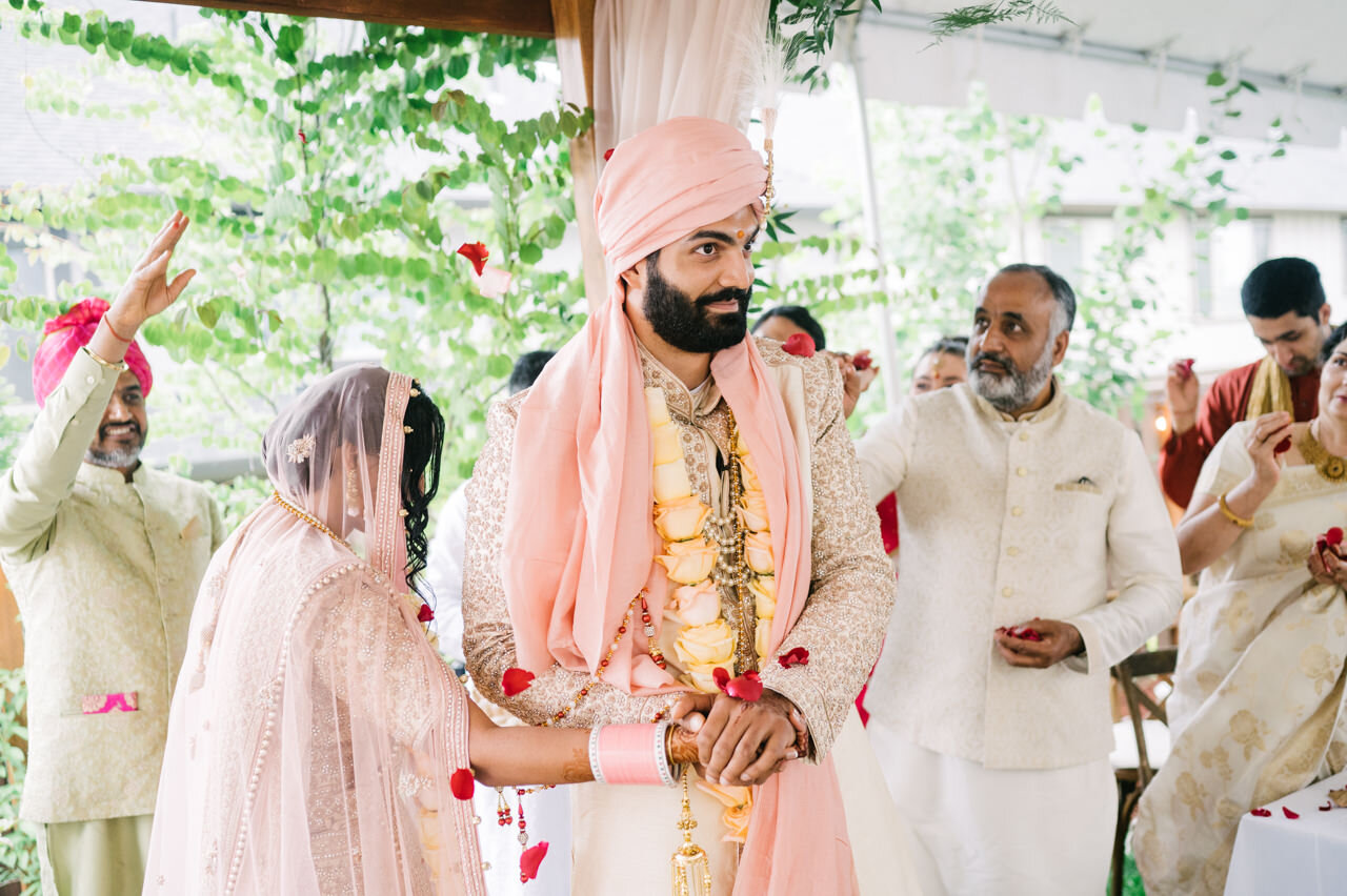  Groom and bride walk saptapadi while guests toss rose pedals 