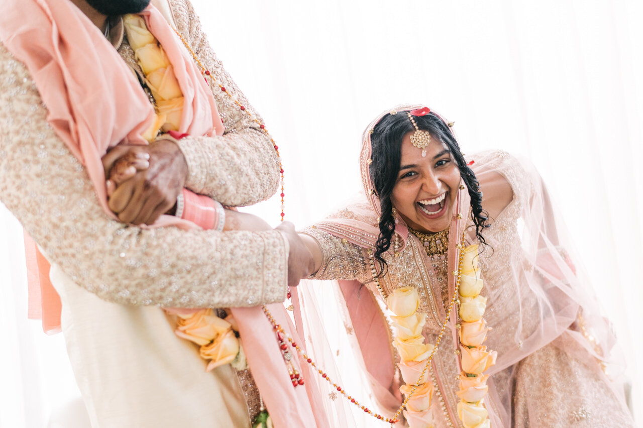  Indian Bride laughing joyfully while sitting down during ceremony 
