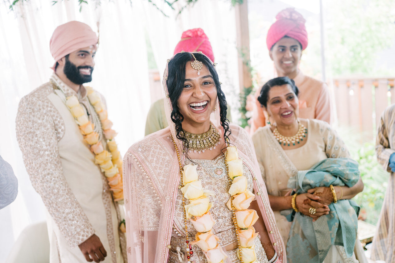  Bride laughs after wedding ceremony surrounded by groom and family 