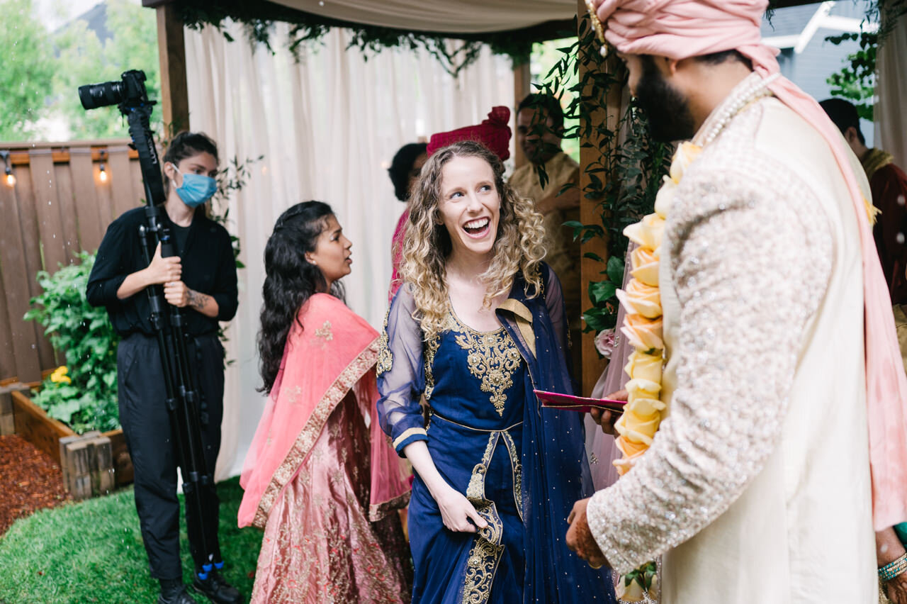  Guest dressed in blue sari smiles at groom under mandap 