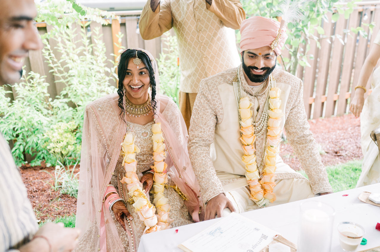  Indian bride and groom seated at backyard reception dinner table 