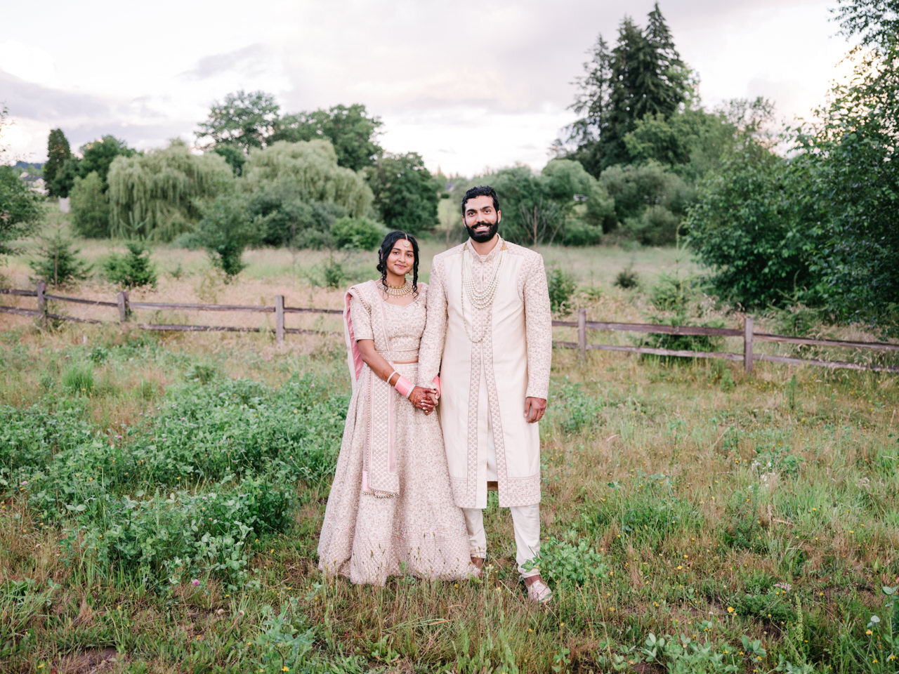  Bride and groom holding hands dressed in pink and gold indian wedding attire 