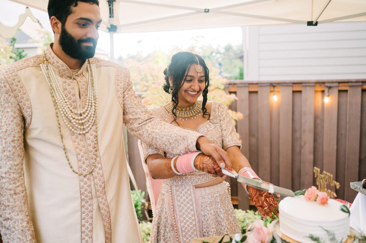  Indian bride and groom cut cake in backyard 