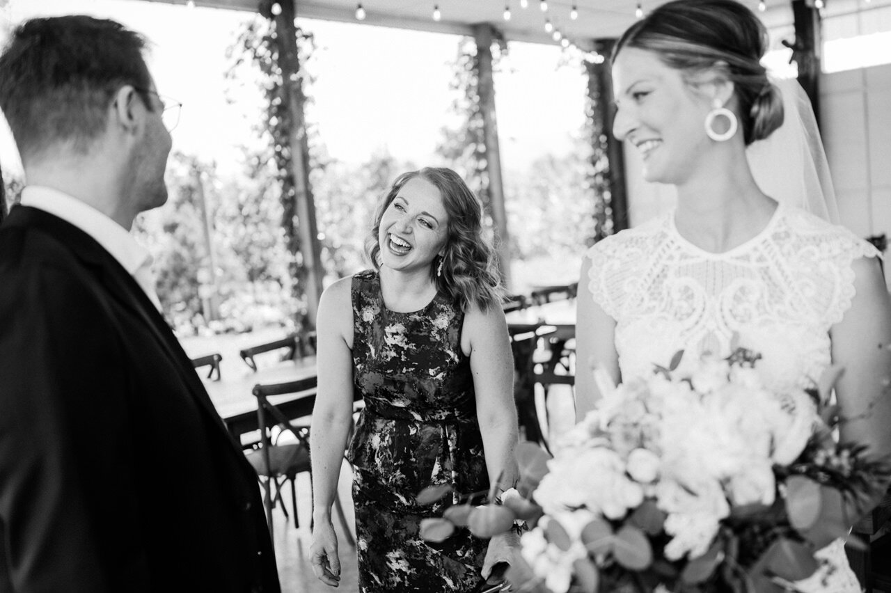  Bride groom and maid of honor laughing together in candid moment 