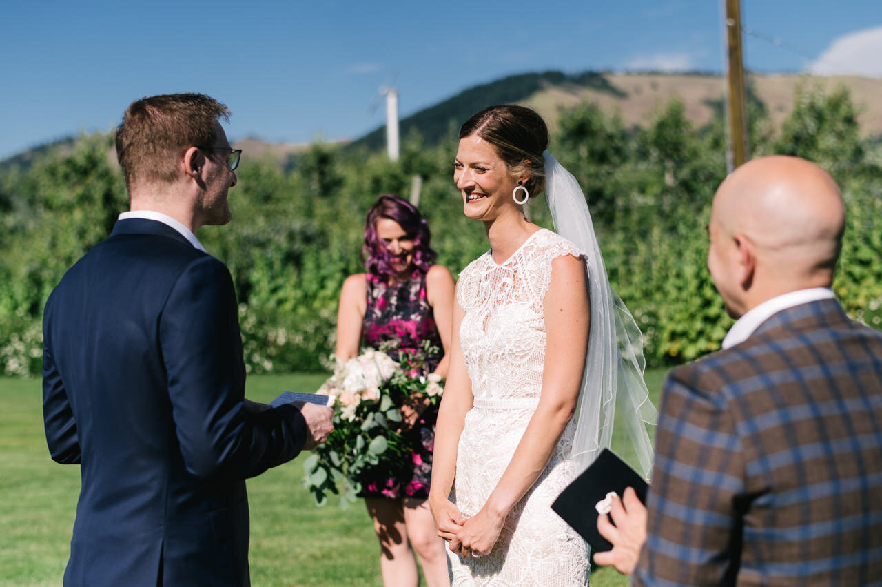  Bride laughing during wedding vows, wearing hoop earings in the sun 