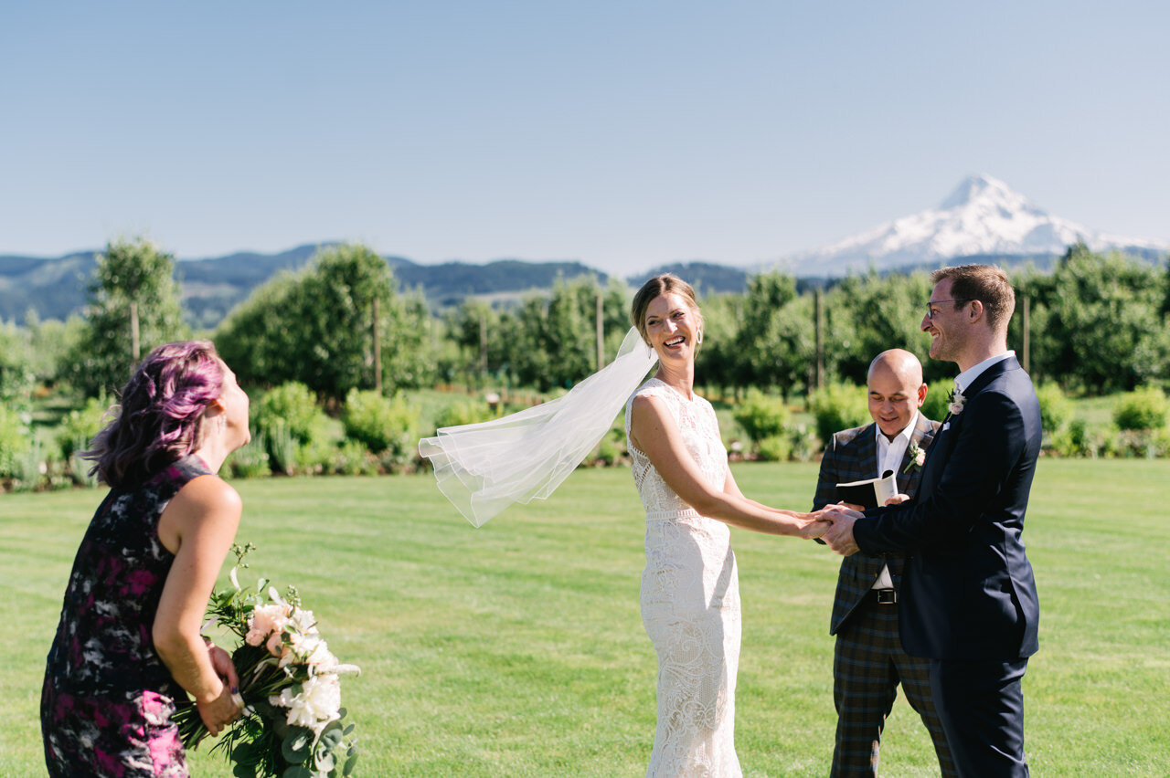  Bride looks at maid of honor laughing at elopement in front of mt hood 