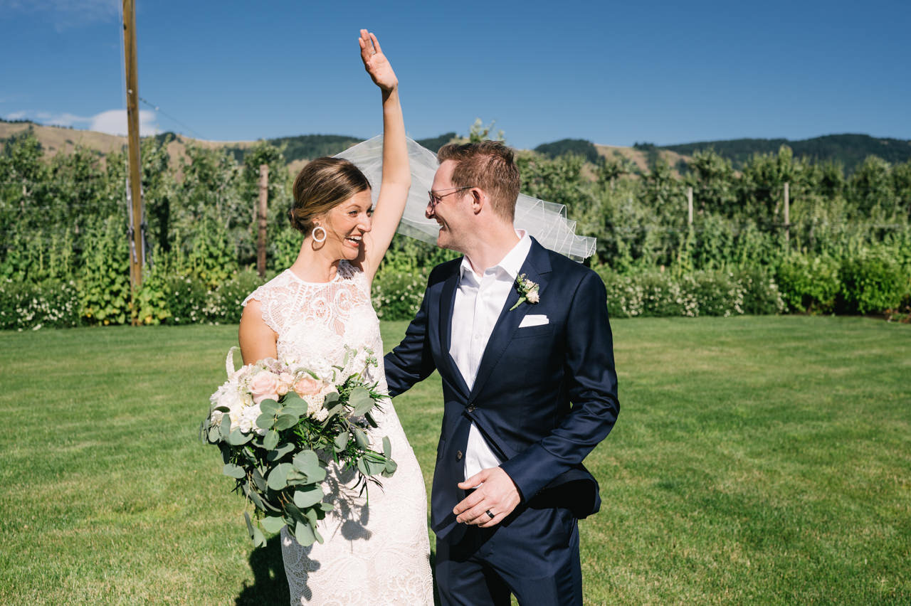  Bride laughs and cheers in front of orchard in hood river 