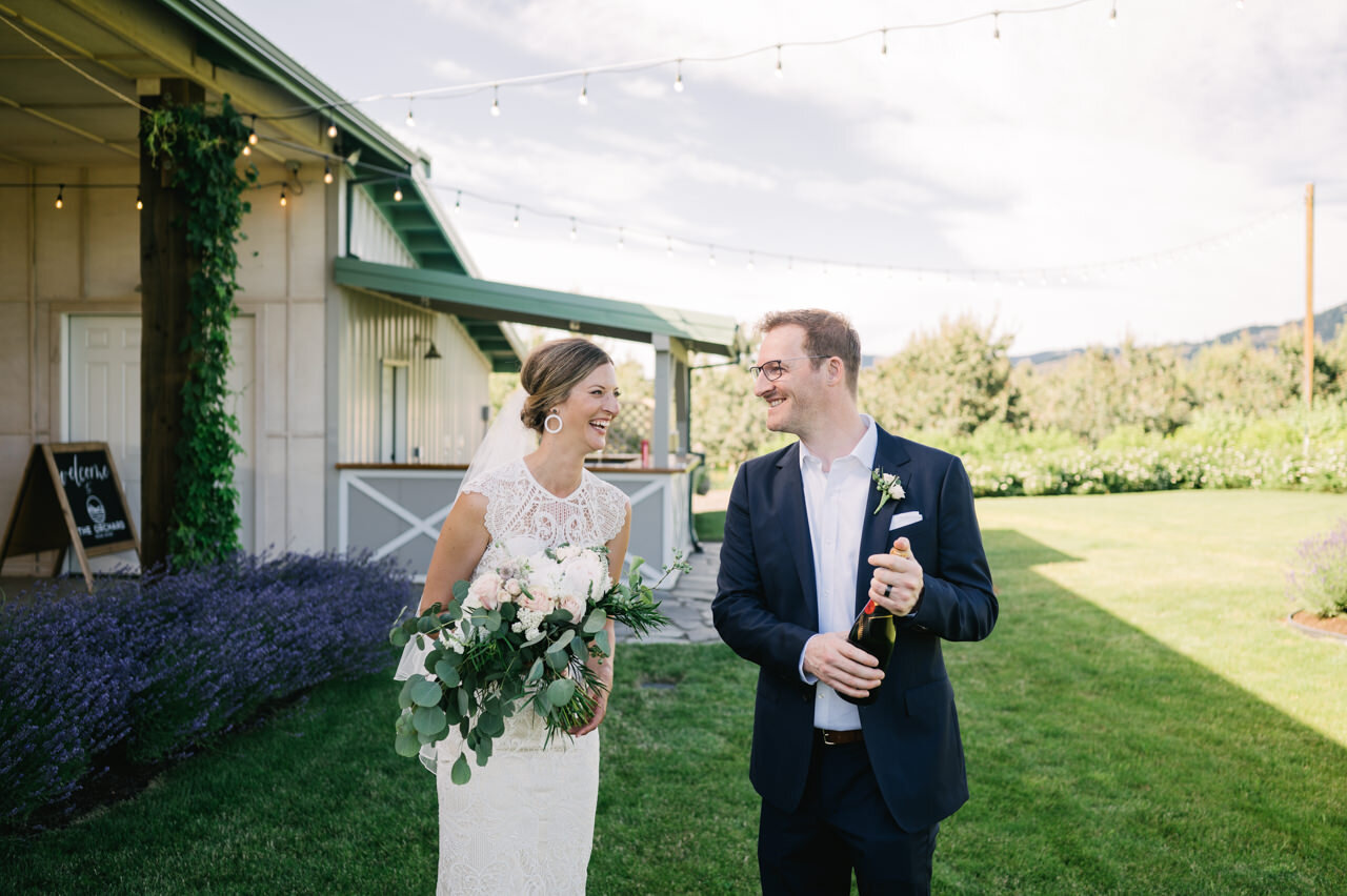  Groom holds champagne bottle with groom during elopement at the orchard 