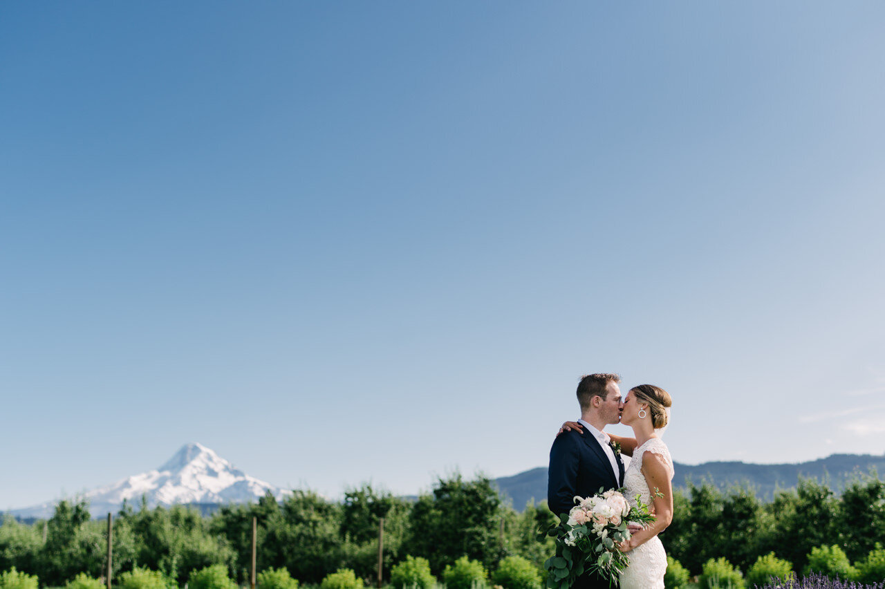  Hood river wedding portrait kissing in front of orchard and mt hood 