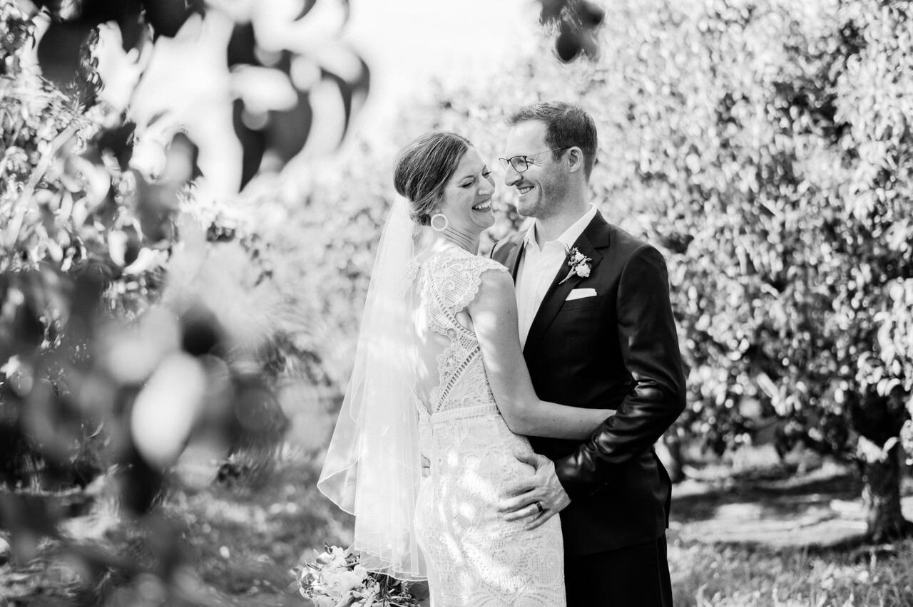  Bride and groom laughing together in orchard 