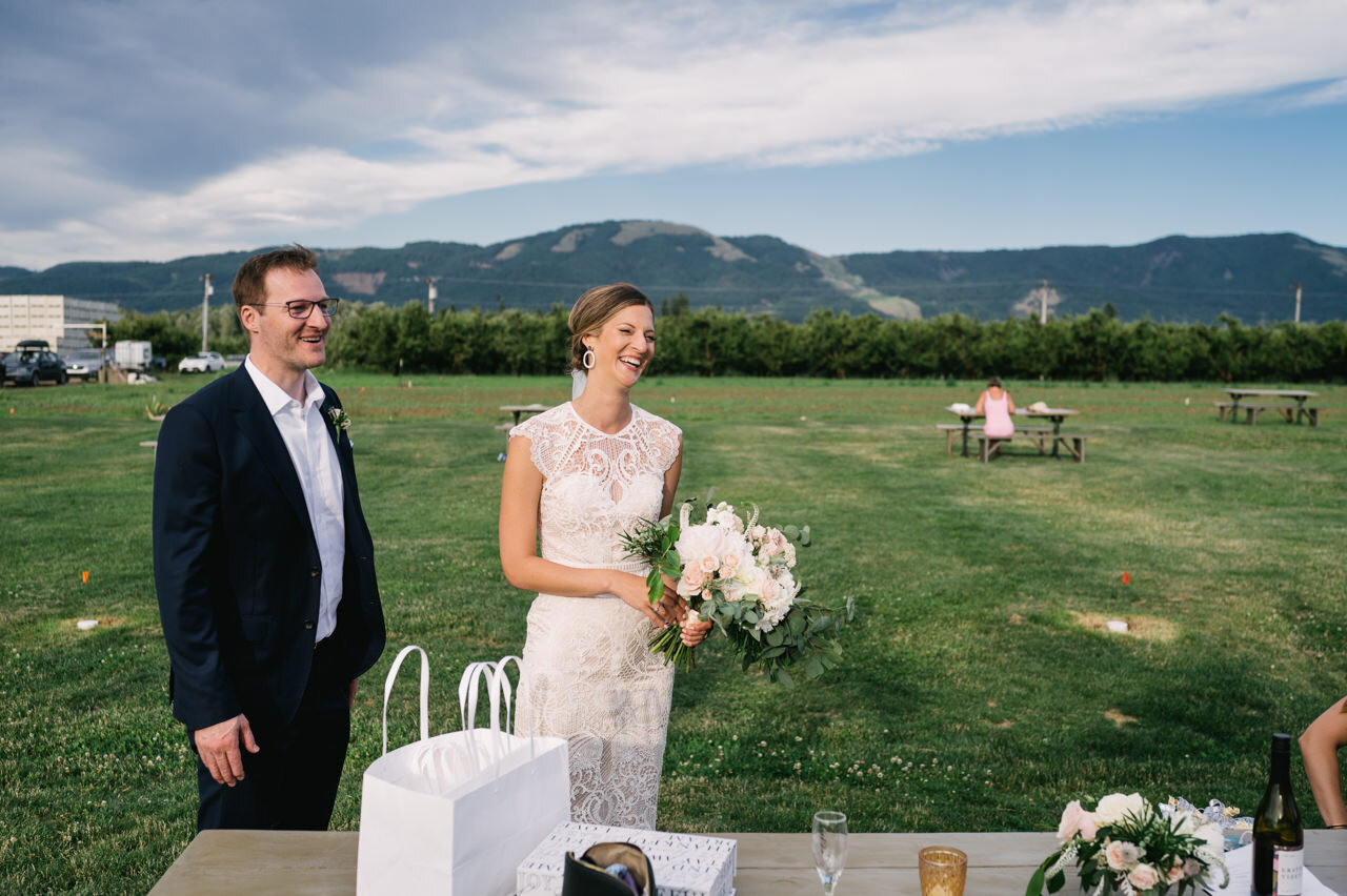  Bride and groom smiling at reception table in hood river valley 