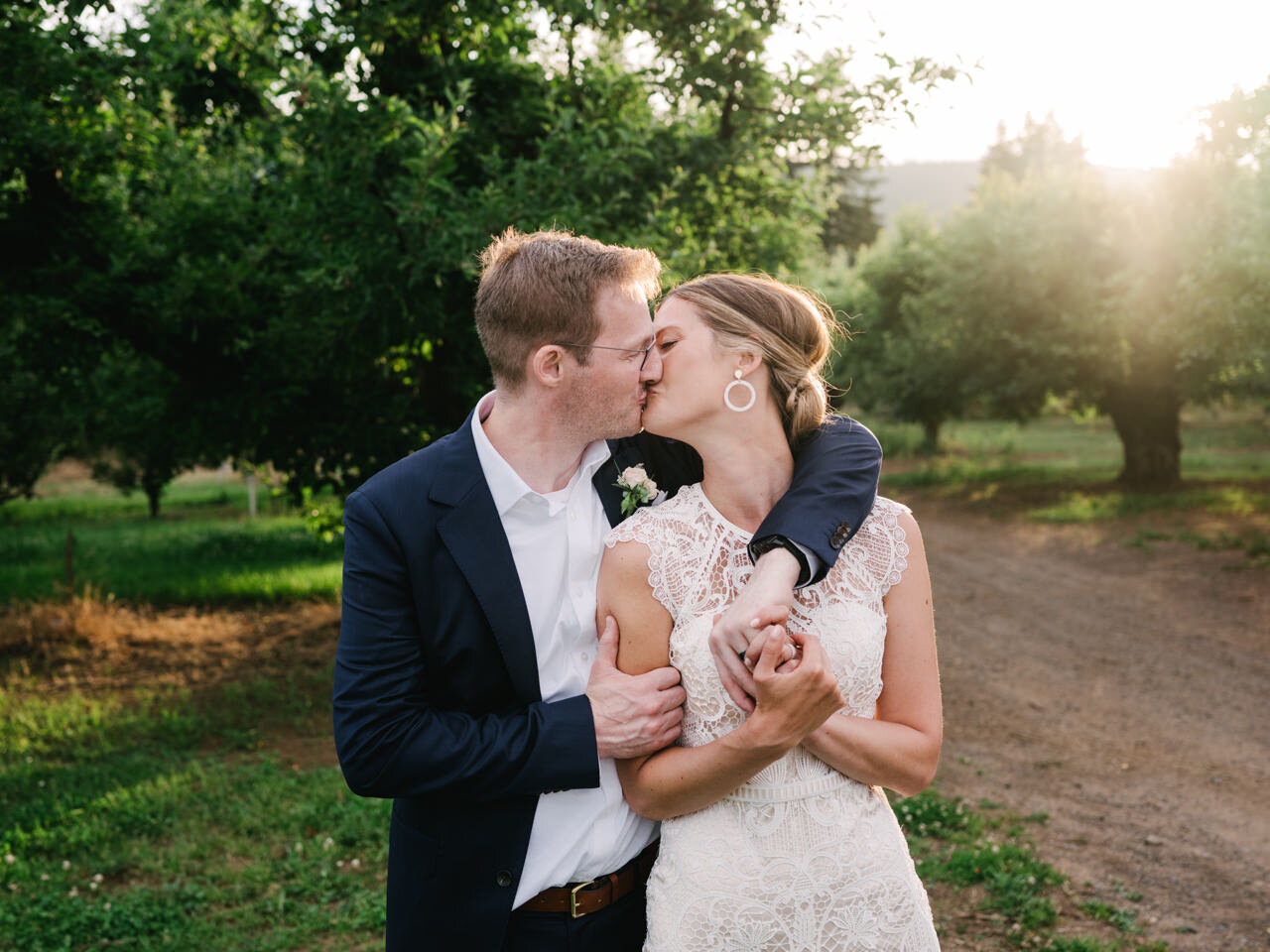  Bride with lace dress and groom kiss in sunlight orchards 