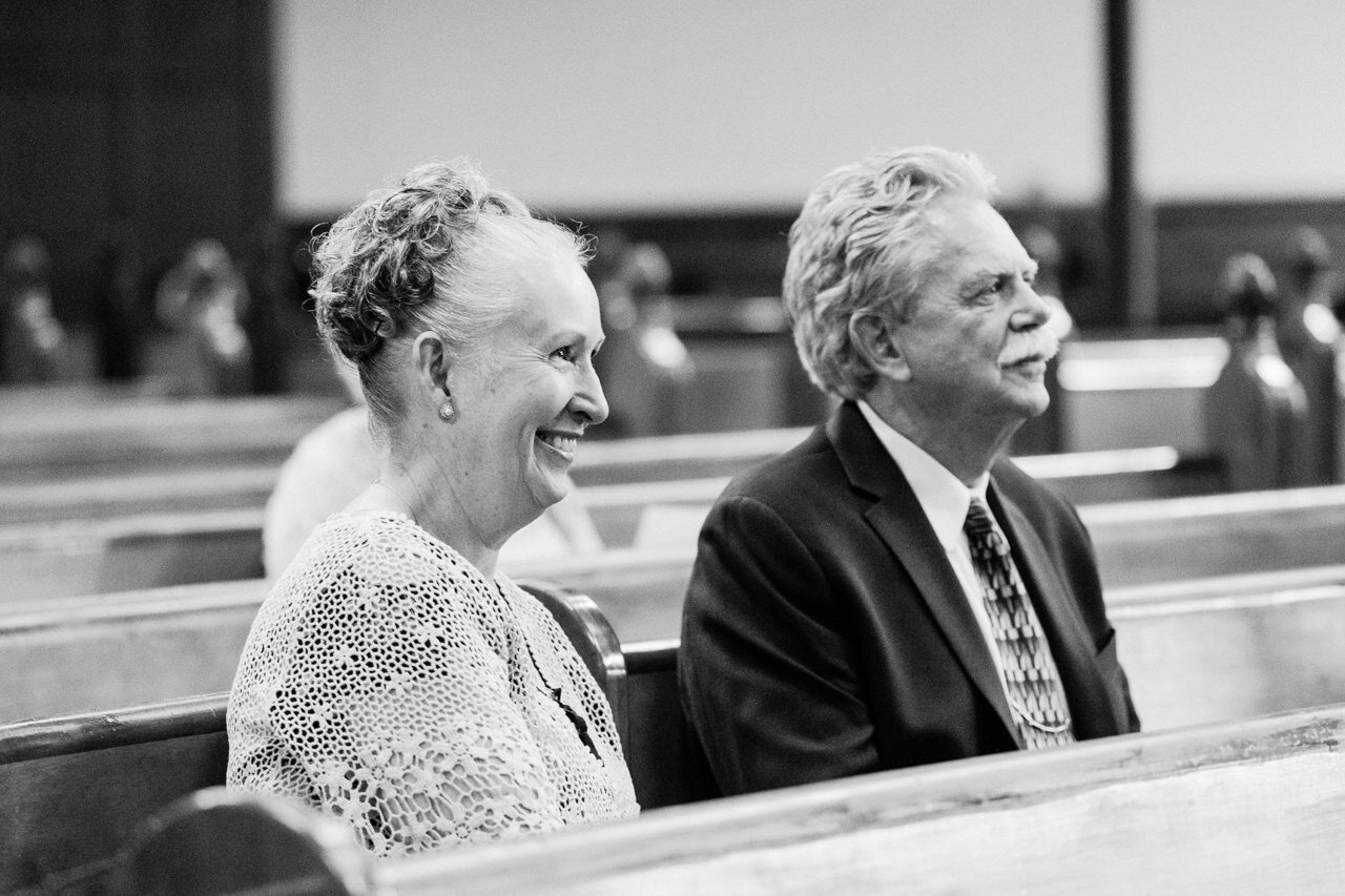  Smiling father and mother of the bride during wedding ceremony 