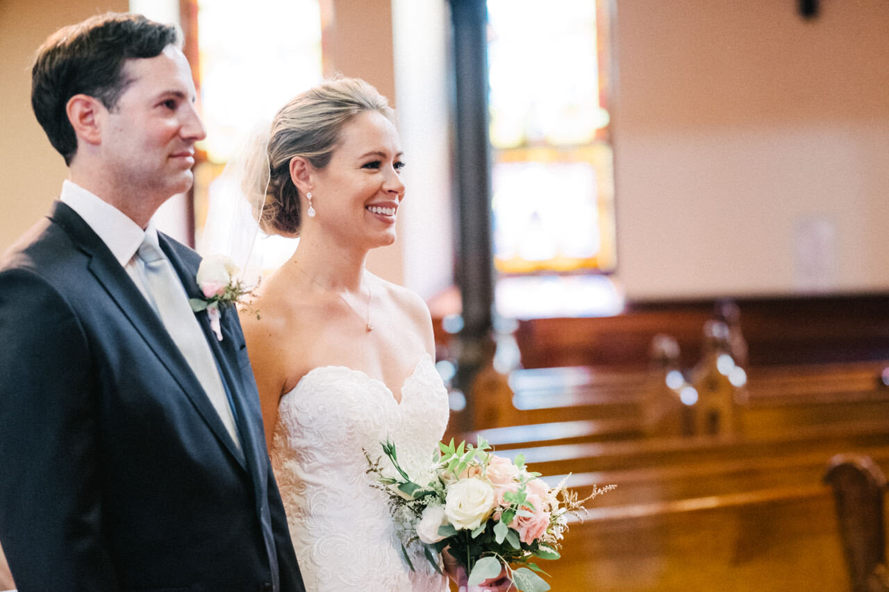  Close up of bride smiling as groom listens to clergy delivery wedding message 
