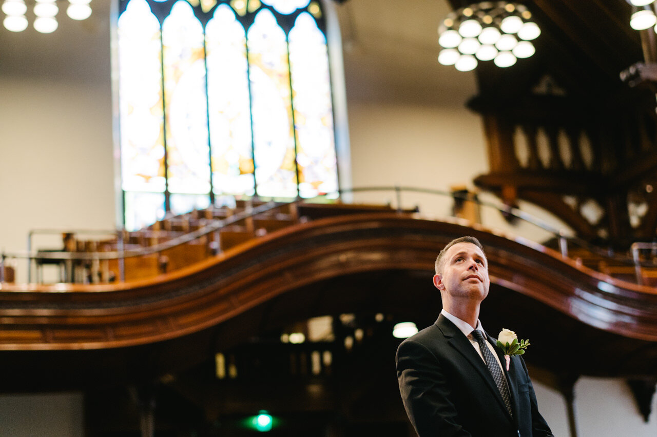  Best man looks up towards the balcony during wedding ceremony 
