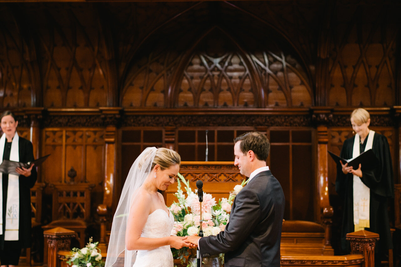  Bride places ring on grooms finger during formal first presbyterian church portland wedding ceremony 