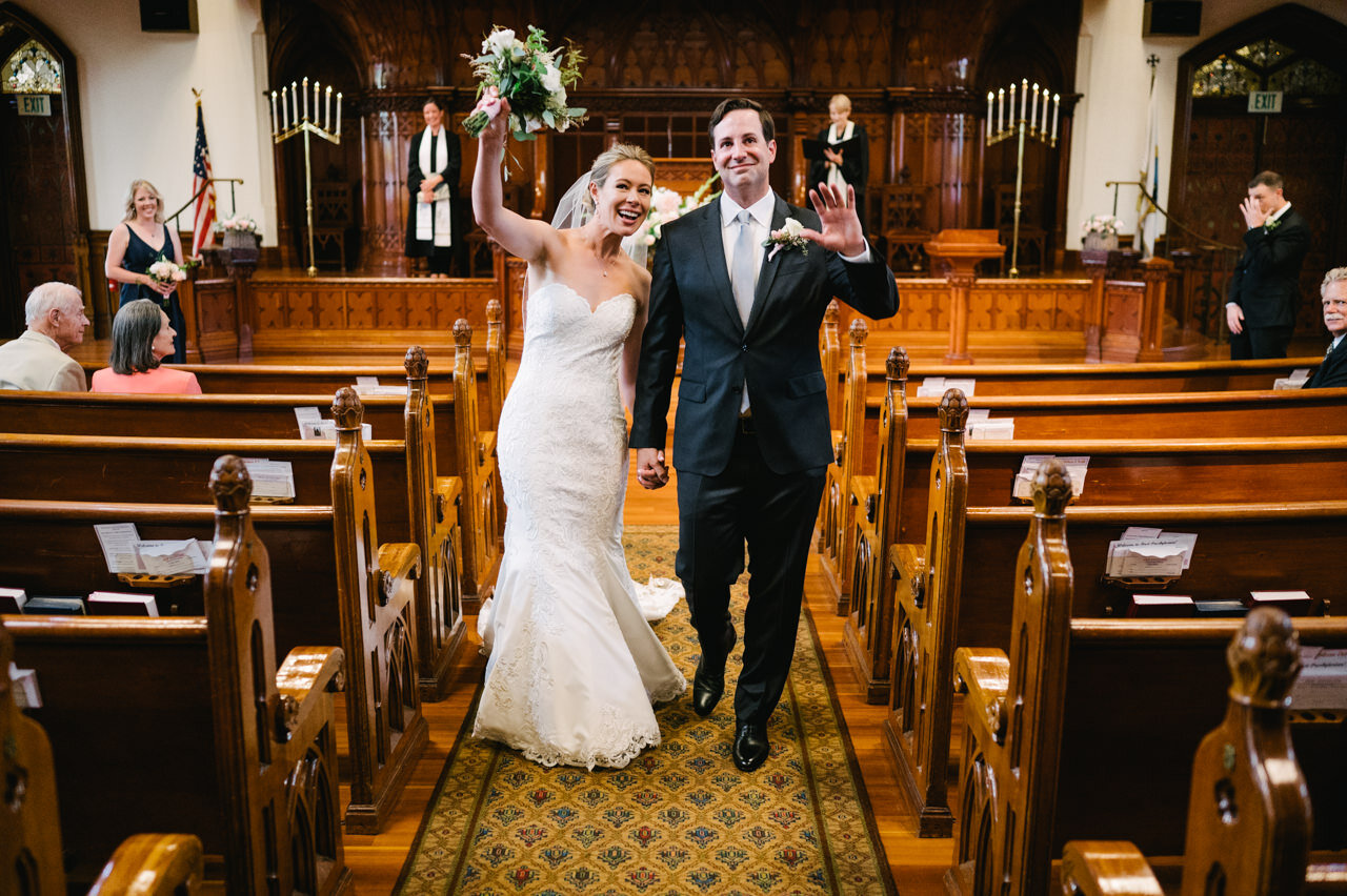  Bride and groom wave up to zoom camera after just married during church wedding 