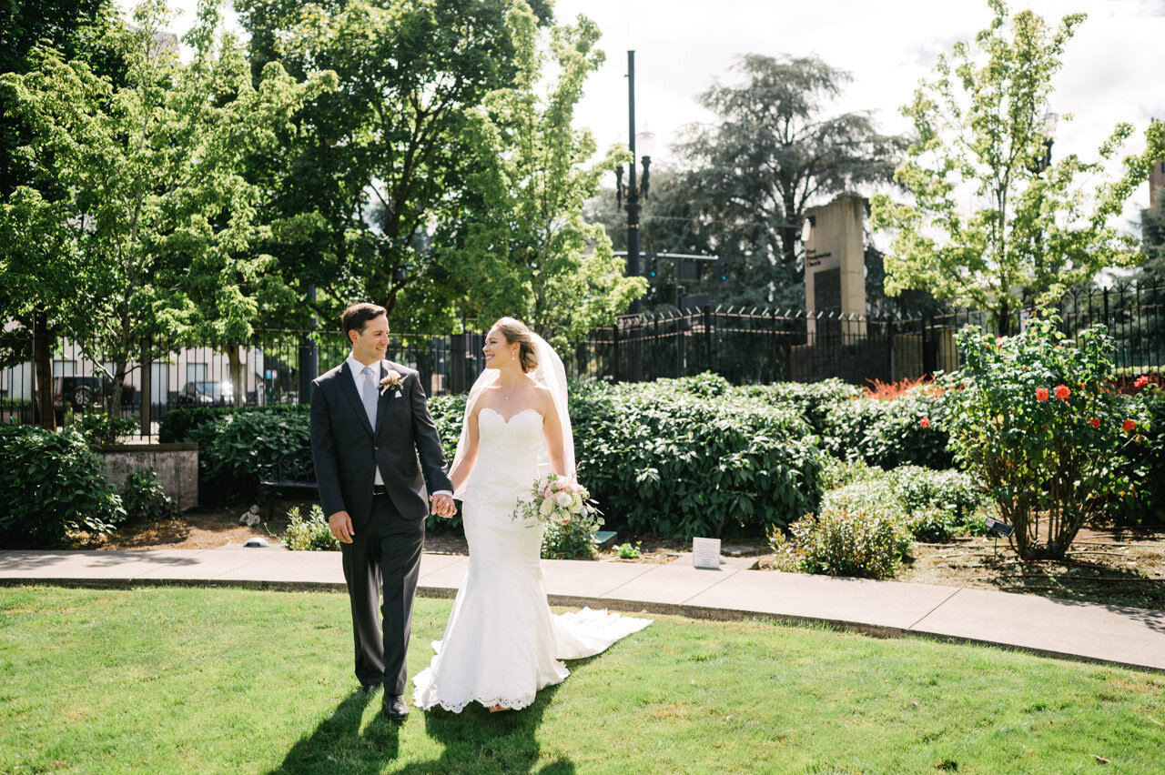  Bride and groom walking in green grass church courtyard with roses 