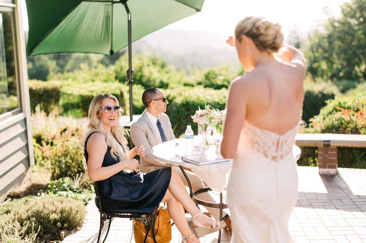  Blonde wedding guest laughing with bride on sunny day 