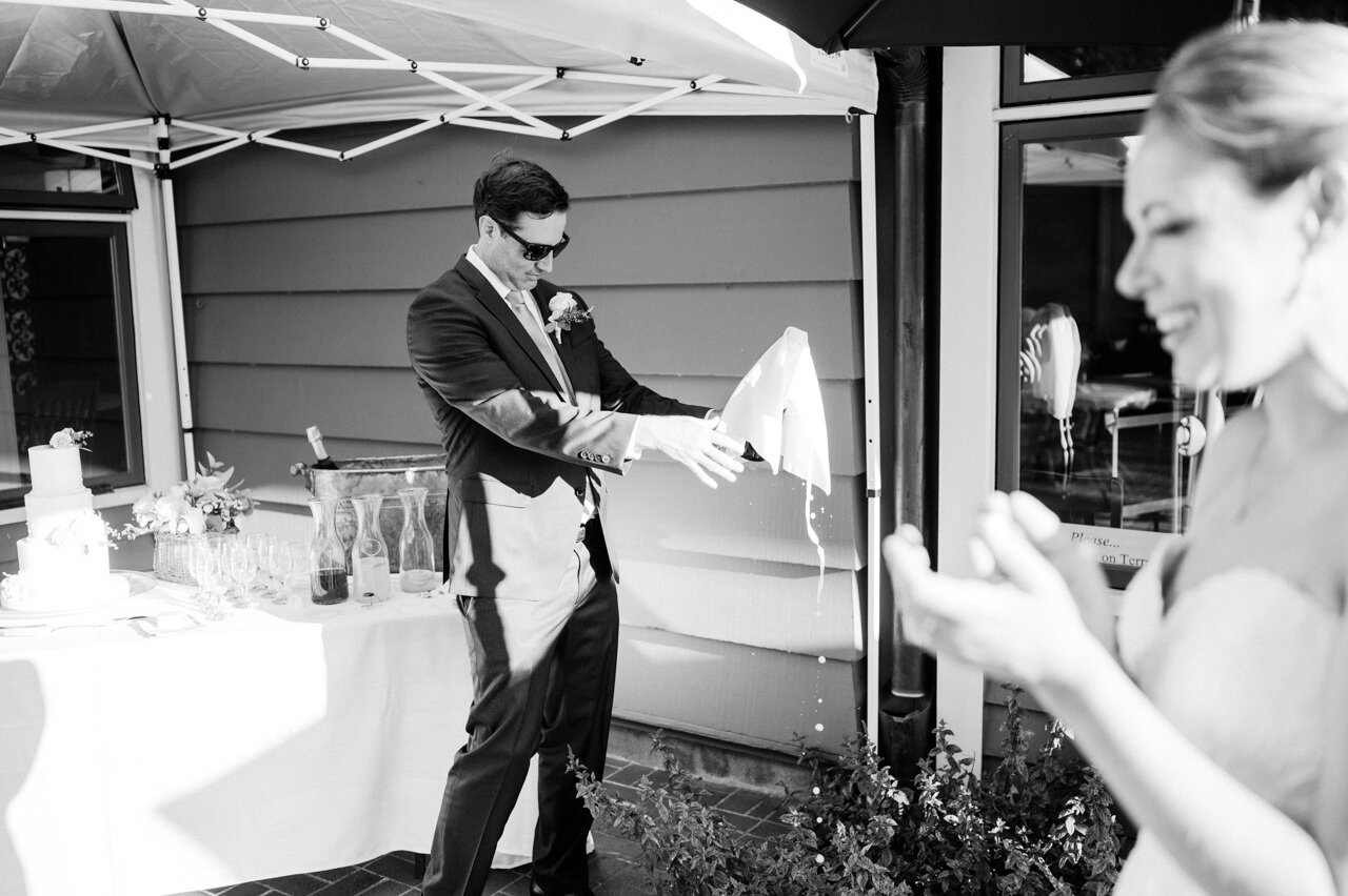  Groom pops champagne with towel as it drips 