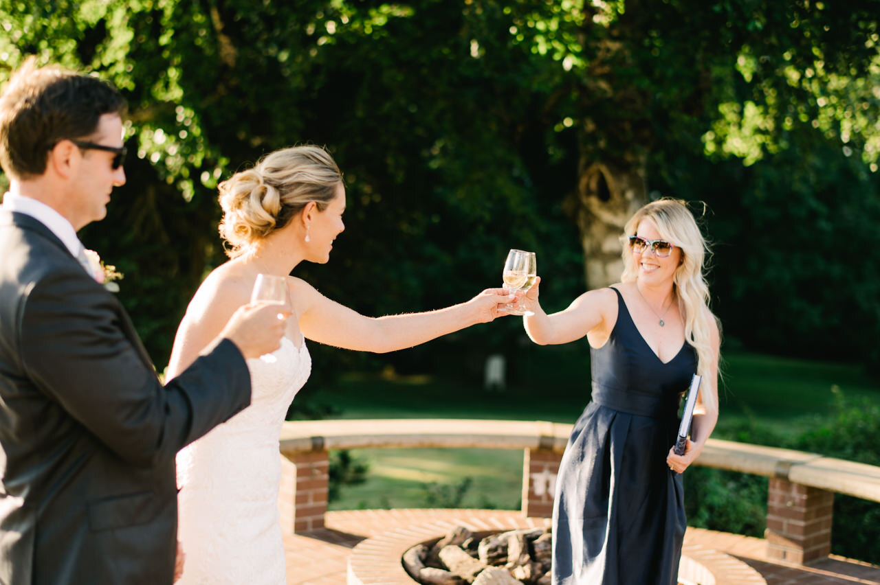  Wedding guest in dark blue dress toasts bride and groom in sunny afternoon 
