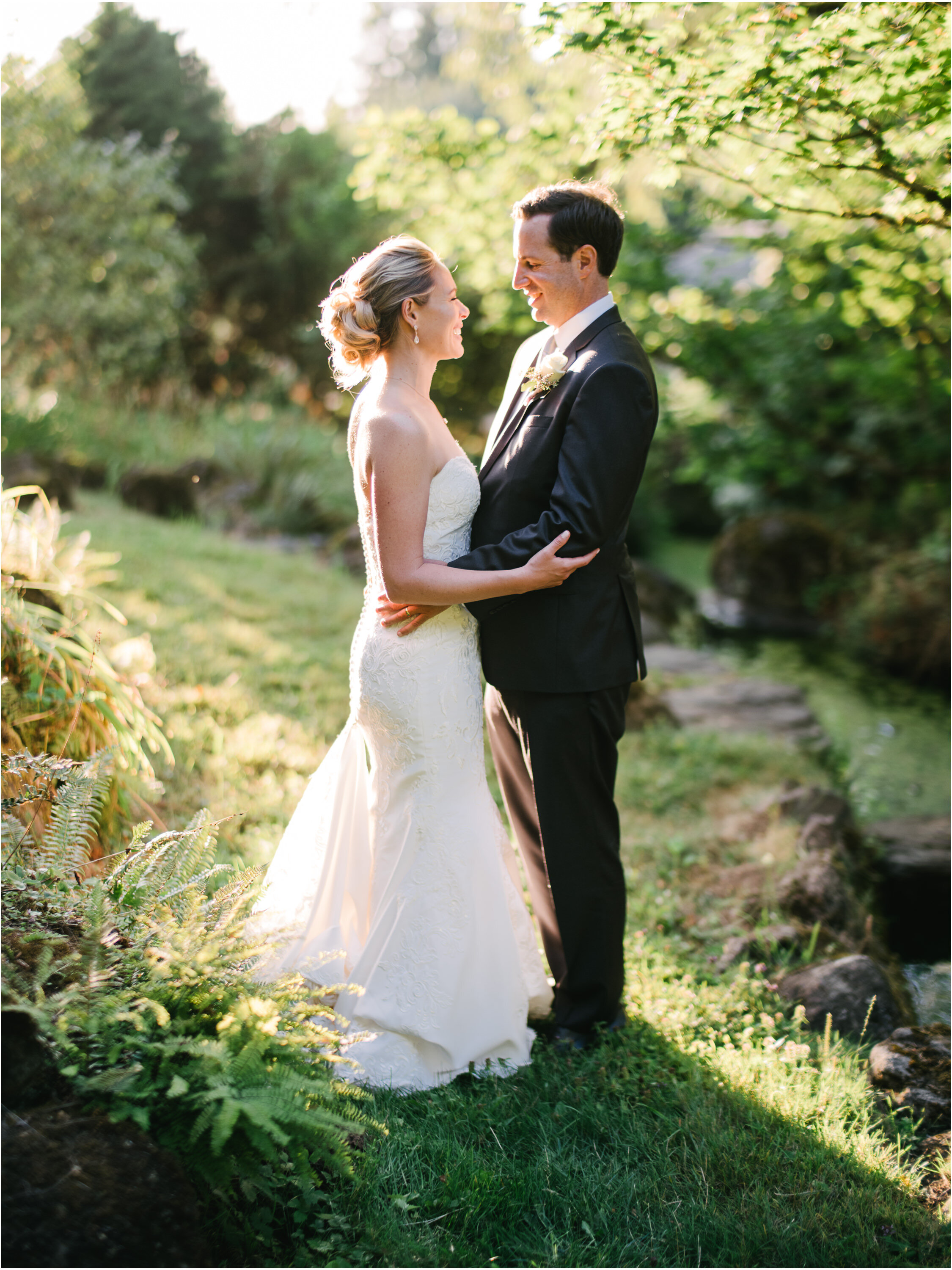  Bride and groom standing by pond backlit by sunlight at menucha retreat center 