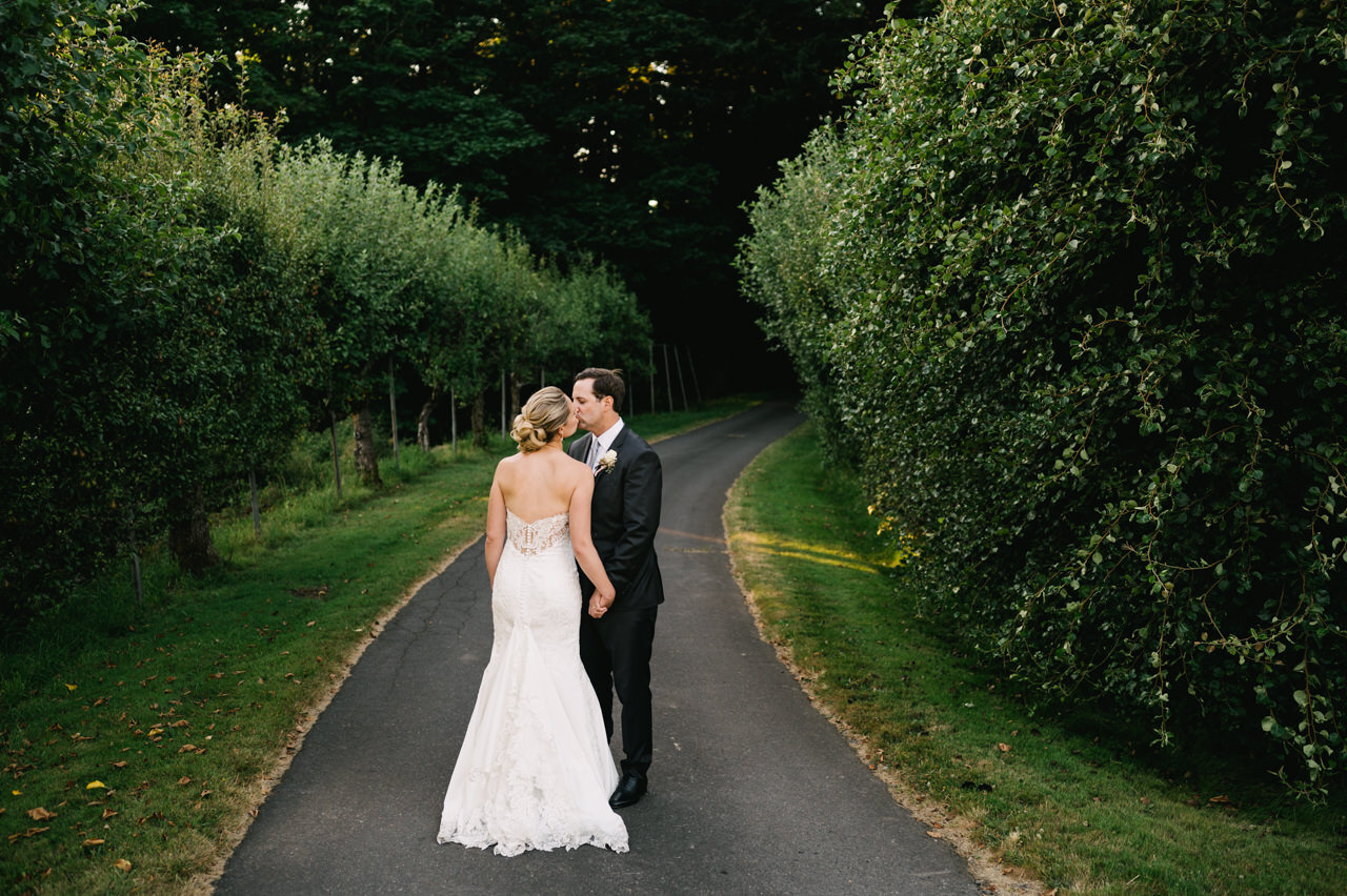  Wedding couple kisses on path through pear orchard 